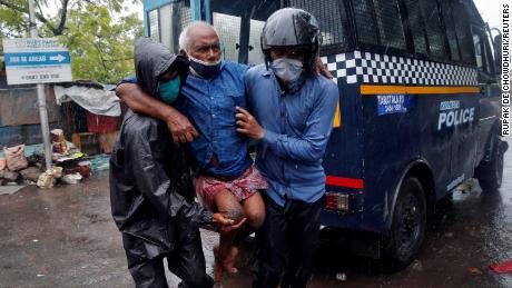 Police officers take a disabled man to a safer place after evacuating from a slum in Kolkata, India.