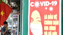 A propaganda poster about preventing the spread of the corona virus was seen on the wall when a man smoked along the street in Hanoi.