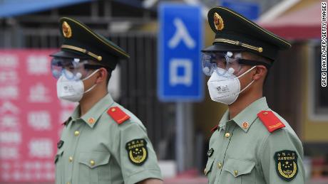 Paramilitary police officers wear masks and goggles as they stand guard at the entrance to the Xinfadi market which was closed in Beijing on June 13.