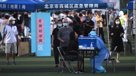 A health worker wearing protective clothing took a wipe test from a woman at a testing center set up for people who visited or lived near the Xinfadi market in Beijing.