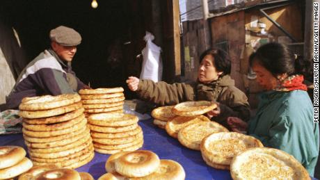 A Uyghur man sells traditional flatbread to female buyers along Beijing's Xinjiang Road in 1999.