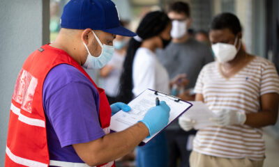 Community outreach specialist Rogelio Bucio collects patient information as they wait in line at a walk up Covid-19 testing site on June 27, in Dallas, Texas.