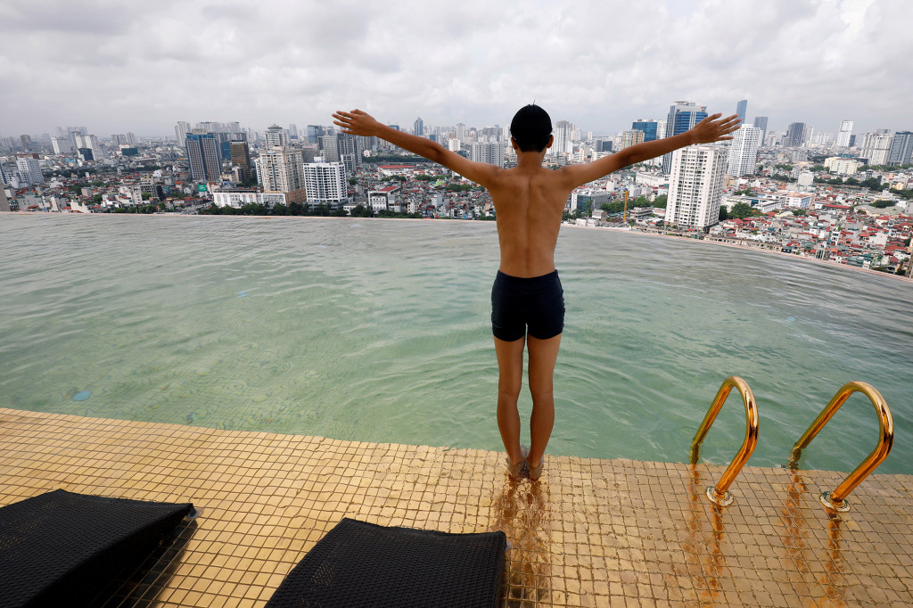 A boy jumps into the water in a gold-plated infinity pool from the newly opened Dolce Hanoi Golden Lake hotel in Hanoi