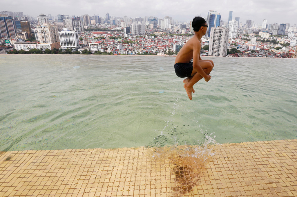 A boy jumps into the water in a gold-plated infinity pool from the newly opened Dolce Hanoi Golden Lake hotel in Hanoi