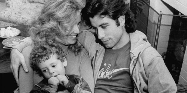 Actor John Travolta w. his arm around actress girlfriend Diana Hyland and her young son Zachary, 4, while sitting together at home.