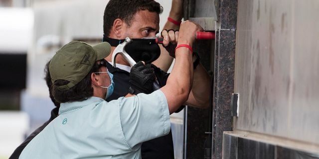 Federal officials and a locksmith work on a door to make entry into the vacated Consulate General of China building Friday, July 24, 2020, in Houston. On Tuesday, the U.S. ordered the Houston consulate closed within 72 hours, alleging that Chinese agents had tried to steal data from facilities in Texas, including the Texas A&amp;M medical system and The University of Texas MD Anderson Cancer Center in Houston. (Brett Coomer/Houston Chronicle via AP)