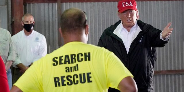 President Donald Trump speaks with first responders as he tours a warehouse being used as a distribution point for relief aid after Hurricane Laura hit the area, Aug. 29, in Lake Charles, La. (AP Photo/Alex Brandon)