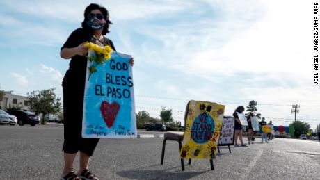 Anna Perez, 53, holds a sign during a drive-thru vigil in El Paso, Texas, honoring the 23 victims in the Walmart shooting on Saturday. 