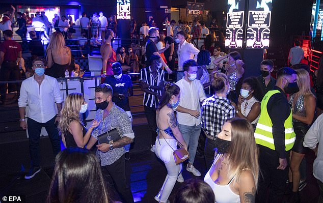 Bars and clubs are to close for three weeks across Italy and people will be required to wear masks in some areas at night after a spike in new cases, particularly in younger people. Pictured: People in a busy Italian club in Rome wear masks while they dance together
