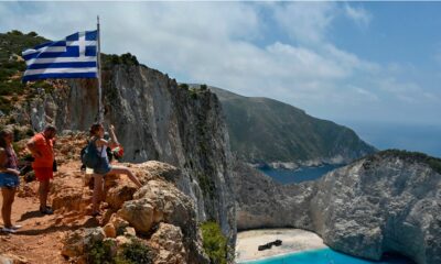 Tourists take pictures and selfies from a rock overlooking the famous Navagio (Shipwreck) beach on the Ionian island of Zakynthos on July 18, 2020. - Usually for the season, there is 20 daily departures for the island's landmark beach, now only four operate daily. (Photo by Louisa GOULIAMAKI / AFP) (Photo by LOUISA GOULIAMAKI/AFP via Getty Images)