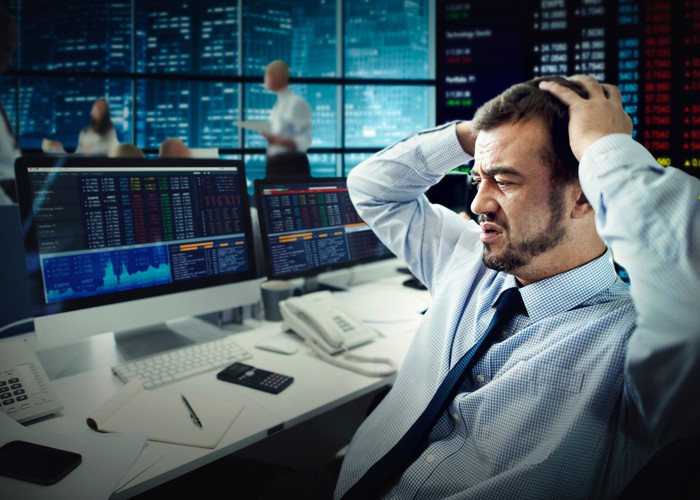A visibly disappointed stock trader stares at his computer screen.