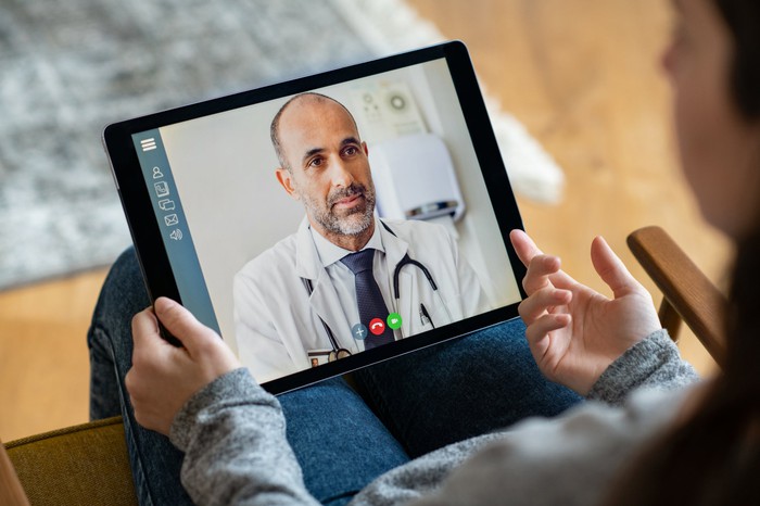 The patient uses the tablet for a virtual consultation with the doctor. 