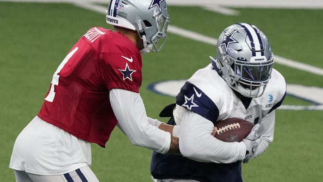 Dallas Cowboys quarterback Duck Prescott (4) handed his arms to fleeing Ezekiel Elliott during an NFL football training camp in Frisco, TX, Monday, Aug 24, 2020 (AP Photo / LM Otero)