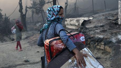A migrant carries his belongings after a devastating fire at the Moriya camp on September 9.