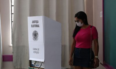 Mulher de máscara vota em uma urna eletrônica